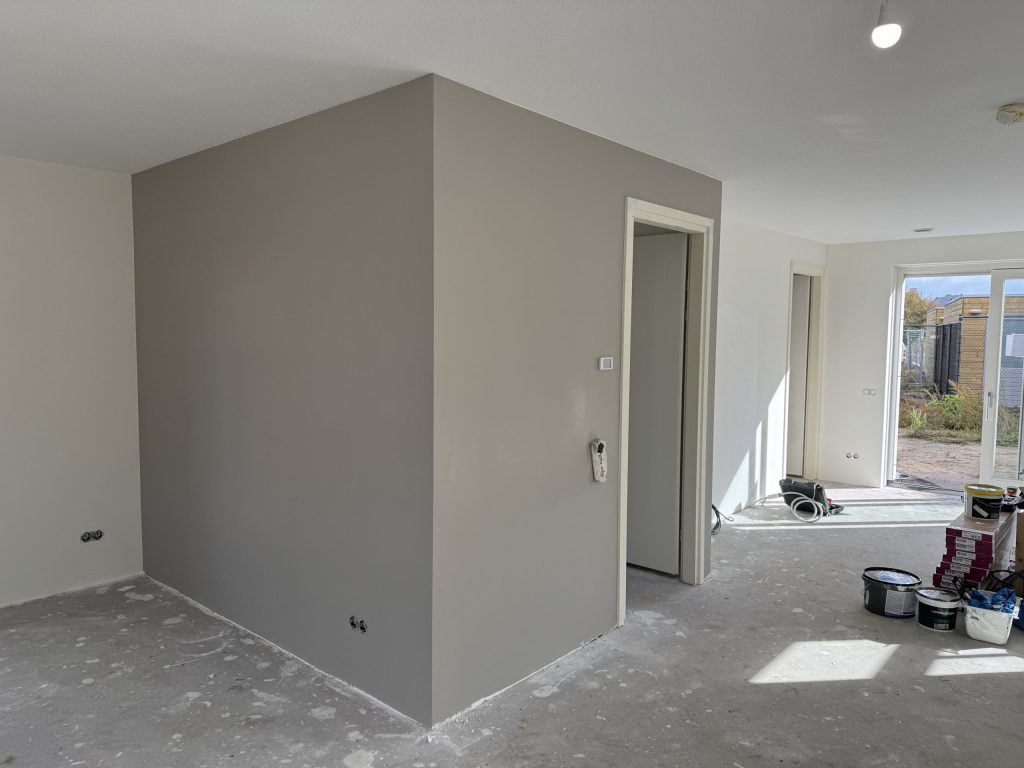 Woonkamer met strak gesausde wanden in een zachte grijstint na het behangen